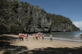 toursits with red life jackets stepping on to the beach at puerto princesa underground river national park in palawan philippines